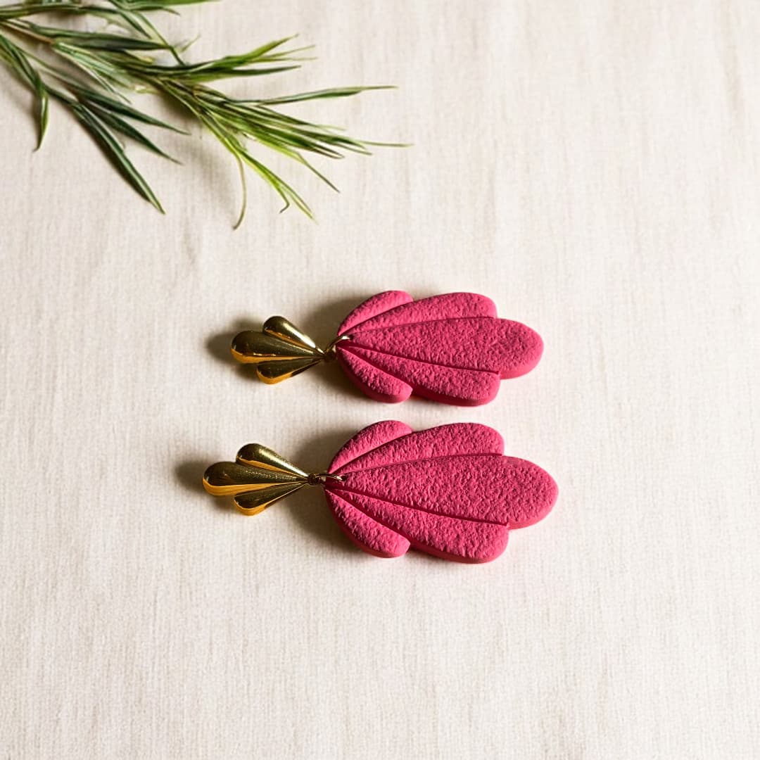 Boucles d’oreilles Flora avec pétales en pâte polymère rose texturée et clous dorés en forme de feuille.