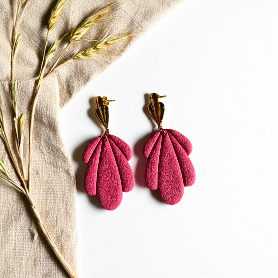Boucles d’oreilles Flora avec pétales en pâte polymère rose texturée et clous dorés en forme de feuille.