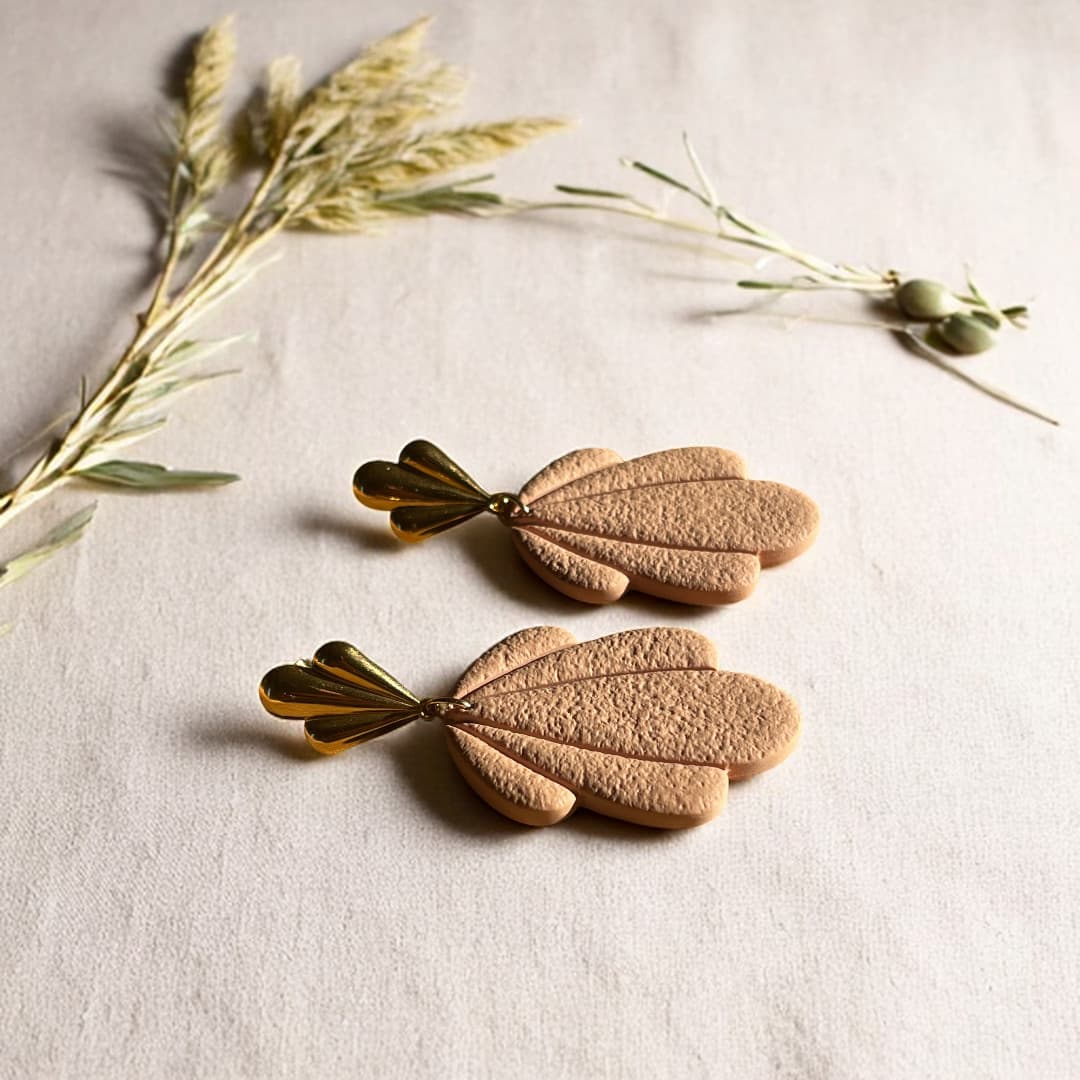 Boucles d’oreilles Flora avec pétales en pâte polymère rose texturée et clous dorés en forme de feuille.