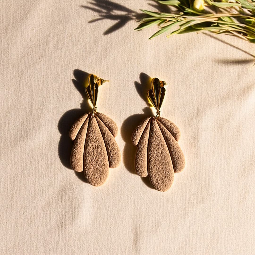 Boucles d’oreilles Flora avec pétales en pâte polymère rose texturée et clous dorés en forme de feuille.