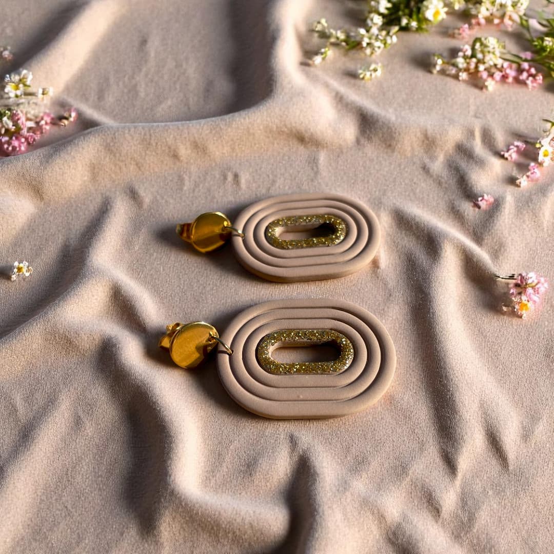 Boucles d’oreilles artisanales Eudora en pâte polymère, avec un liséré doré scintillant et une attache en acier inoxydable doré.
