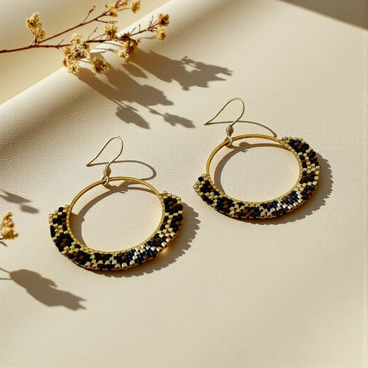 Boucles d’oreilles Naya tissées à la main en perles Miyuki Delica dorées, cognac et noires, motif léopard sur créole dorée.