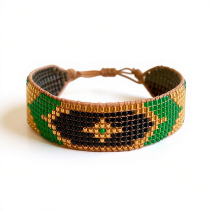 Photo d'un bracelet manchette Miyuki modèle Kemet tissé main. Le motif est composé de perles Doré, Vert Émeraude et Black Moss sur fond blanc.