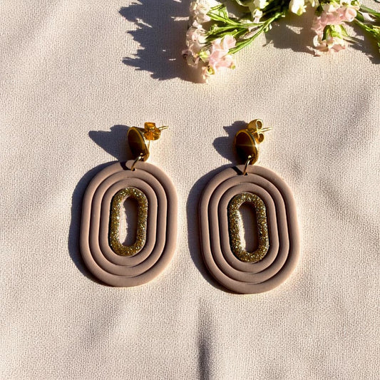 Boucles d’oreilles artisanales Eudora en pâte polymère, avec un liséré doré scintillant et une attache en acier inoxydable doré.