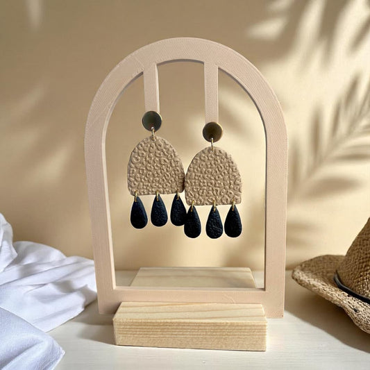 Boucles d’oreilles pendantes en polymère beige avec motif léopard texturé, pampilles noires texturées et attaches dorées.