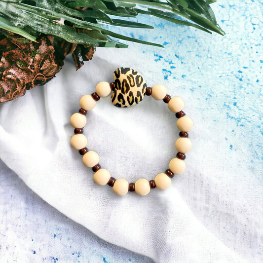 Bracelet en perles rondes de couleur blanc cassé et marron avec une perle centrale ne forme de coeur au motif Léopard